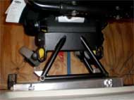 This figure shows three pictures of  a) manual wheelchair secured by 4-point strap-type tiedown; b) top view of UDIG auto docking system;  c) powered wheelchair in rear-facing passenger station (RF-WPS) 